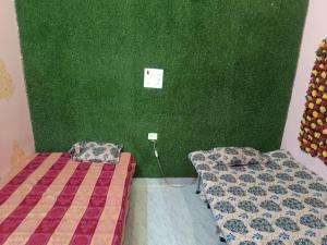 2 Betten in einem Zimmer mit grüner Wand in der Unterkunft Shree Banke bihari home stay in Mathura