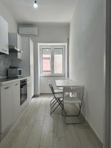 a white kitchen with a table and chairs in it at Rent House Scauri in Minturno