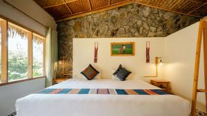 een slaapkamer met een bed in een kamer met een stenen muur bij Sapa Eco Bungalows & Spa in Sa Pa