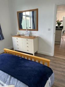 a bedroom with a bed and a dresser with a mirror at Guest Suite in Porthleven With Private Garden in Helston