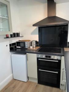 a kitchen with a black stove and a microwave at Guest Suite in Porthleven With Private Garden in Helston