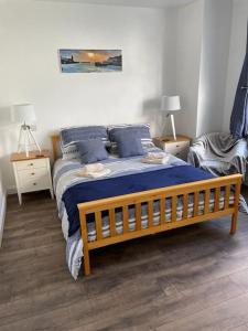 een slaapkamer met een houten bed met blauwe kussens bij Guest Suite in Porthleven With Private Garden in Helston