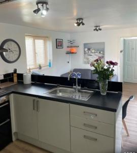 een keuken met een wastafel en een klok aan de muur bij Guest Suite in Porthleven With Private Garden in Helston