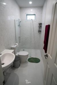 La salle de bains blanche est pourvue de toilettes et d'un lavabo. dans l'établissement Kanchanaburi Modern Home, à Kanchanaburi