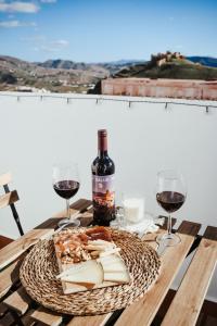 un plato de queso y vino en una mesa con copas de vino en Casita Molino de Erillas en Alora