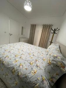 a bed with a blue comforter with flowers on it at RIAN GUEST HOUSE in Sarandë
