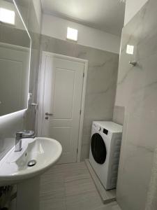 a white bathroom with a sink and a washing machine at RIAN GUEST HOUSE in Sarandë