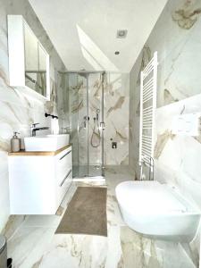 uma casa de banho branca com um lavatório e um chuveiro em AR Living Vienna Apartments & Suites em Viena