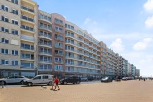 une femme qui marche un chien devant un grand bâtiment dans l'établissement Appartement Mariakerke-Bad Zeezicht, à Ostende