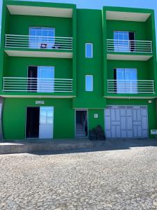 un edificio verde con porte e finestre bianche di Casa Tchitchi a São Filipe