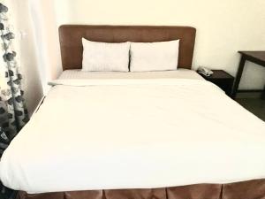 a bed with white sheets and a brown headboard at EL ELOLO Hotel in Dzake