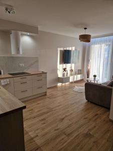 a kitchen and living room with wooden floors and a couch at Baśniowy apartament in Sztutowo