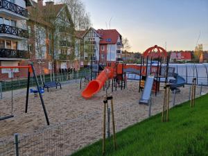 a playground with a red slide in the sand at Baśniowy apartament in Sztutowo