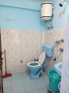 y baño con aseo azul y lavamanos. en Namaste Bhagsu - Rooms & Rooftop Cafe en Dharamshala