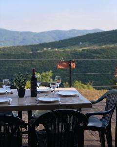 una mesa de madera con copas de vino y una botella de vino en Private Cottage in Tbilisi Area - Napetvrebi Hills en Mskhaldidi