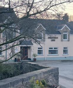 un bâtiment blanc avec une porte rouge dans une rue dans l'établissement Penybont Restaurant + Inn, à Carmarthen