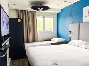 ニームにあるibis Nîmes Ouest - A9のベッド2台とテレビが備わるホテルルームです。