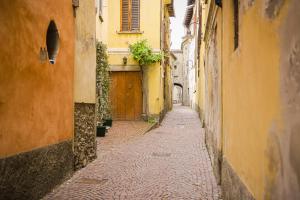 an alley with yellow buildings and a wooden door at Appartamento San Carlo in Tirano