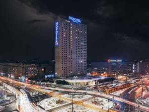 ein hohes Gebäude mit einem Schild darüber in der Nacht in der Unterkunft Novotel Warszawa Centrum in Warschau