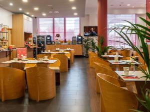 a restaurant with wooden tables and yellow chairs at Ibis Malaga Centro Ciudad in Málaga