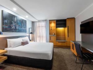 een hotelkamer met een groot bed en een televisie bij Mercure Brisbane King George Square in Brisbane