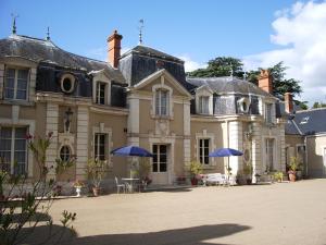 une grande maison avec des parasols en face de celle-ci dans l'établissement Château de Colliers, à Muides-sur-Loire