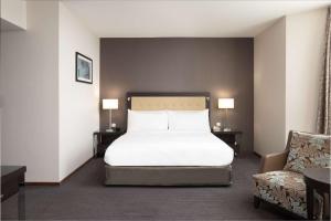 una camera con un letto bianco e una sedia di DoubleTree by Hilton Luxembourg a Lussemburgo