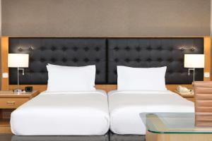 duas camas num quarto de hotel com duas lâmpadas em DoubleTree by Hilton Luxembourg no Luxemburgo