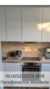 a kitchen with white cabinets and a stove top oven at Ferienwohnung Alpenflair mit Pool und Sauna & direkt am Skilift in Missen-Wilhams