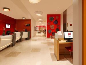 un hall aux murs rouges et une salle d'attente dans l'établissement ibis Coimbatore City Centre - An Accor Brand, à Coimbatore