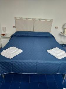 - un lit bleu avec 2 serviettes blanches dans l'établissement La dimora, à Vietri