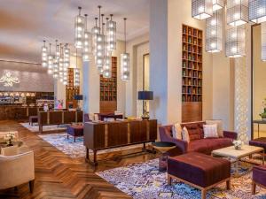 una biblioteca con sofás, sillas y lámparas de araña en Alwadi Hotel Doha - MGallery, en Doha