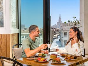 Un uomo e una donna seduti a tavola mangiando cibo di Alwadi Hotel Doha - MGallery a Doha