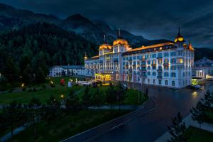 ein großes Gebäude mit nachts eingeschaltetem Licht in der Unterkunft Grand Hotel des Bains Kempinski in St. Moritz