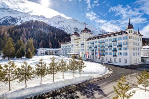 サンモリッツにあるGrand Hotel des Bains Kempinskiの山の前に木々が植えられた白い大きな建物