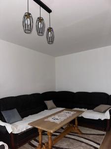 a living room with a black couch and a wooden table at Rogatica Trg oslobodilaca in Rogatica