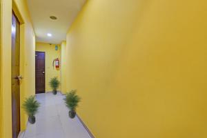 un couloir avec un mur jaune et deux plantes dans l'établissement Collection O Hotel Raj Palace, à Sātej