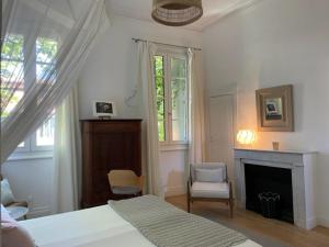 a white bedroom with a bed and a fireplace at Belle maison, 3 chambres,avec un bassin, un jardin , dans le centre historique in Montpellier