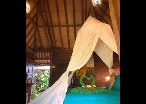 a bedroom with a bed with a canopy and a heart decoration at Villa Kepuh in Kubutambahan