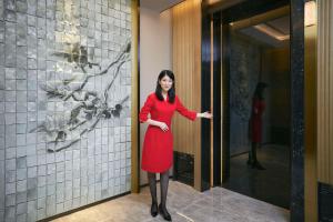 Eine Frau in einem roten Kleid, die vor einer Tür steht. in der Unterkunft Kempinski Residences Guangzhou 广州德安丽舍凯宾斯基酒店 in Guangzhou
