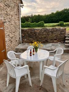 een witte tafel en vier stoelen met flessen en bloemen bij Casa da Forxa, renovated former forge/ smithy in Lugo