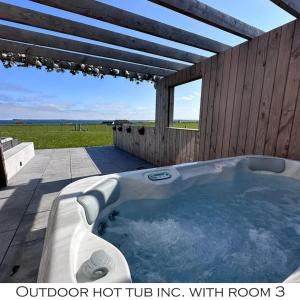 a hot tub on a patio with a roof at Flotnar Hús - Ensuite Rooms in Keiss