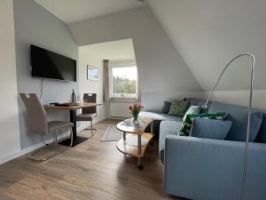 ein Wohnzimmer mit einem blauen Sofa und einem Tisch in der Unterkunft Kapitänshaus " Passat " in Wittdün