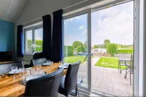 comedor con mesa y sillas y ventana grande en Bungalow de Zwanenbloem, en Wervershoof