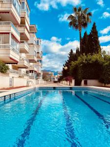 una piscina frente a un edificio con palmeras en Apartment Sunny Albir en Albir