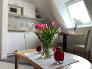 un vase de fleurs roses assis sur une table dans l'établissement Kapitänshaus " Passat ", à Wittdün