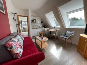 ein Wohnzimmer mit einem roten Sofa und einer Küche in der Unterkunft Kapitänshaus " Passat " in Wittdün