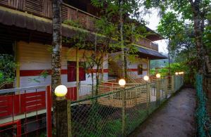 a fence in front of a building with lights on it at Bestinn Leisure Chalona Munnar in Munnar