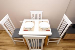 a white dining room table with two chairs and a white table and chairsuggest at Mezani Guest House in Vlorë