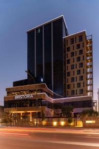 a tall building with a sign in front of a street at Bristoria Hotel Erbil in Erbil